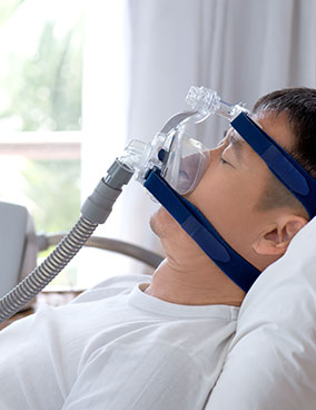 A person lying comfortably in bed with a CPAP mask in place